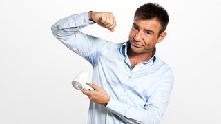 Schwitzen – die Klimaanlage des Körpers Mann fönt einen Schweißflecken auf dem Hemd