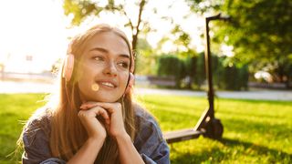 Junge Frau auf einer Wiese und im Hintergrund ist ein eScooter zu sehen