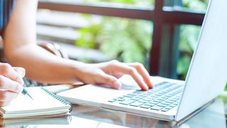 Junge Frau arbeiten am Laptop und hat einen Stift in der Hand