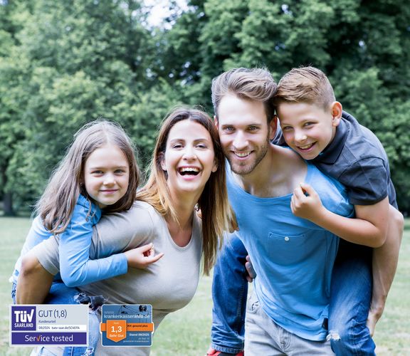 Eine Kassenlänge vorn Vater und Mutter tragen ihre Kinder in einem Park Huckepack