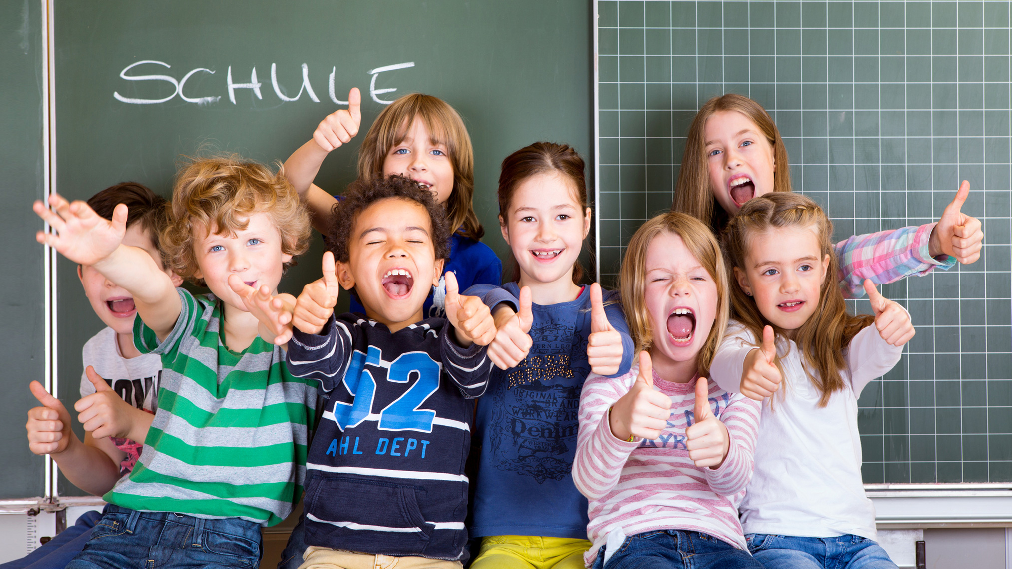 Schulkinder sitzen vor einer tafel und lachen