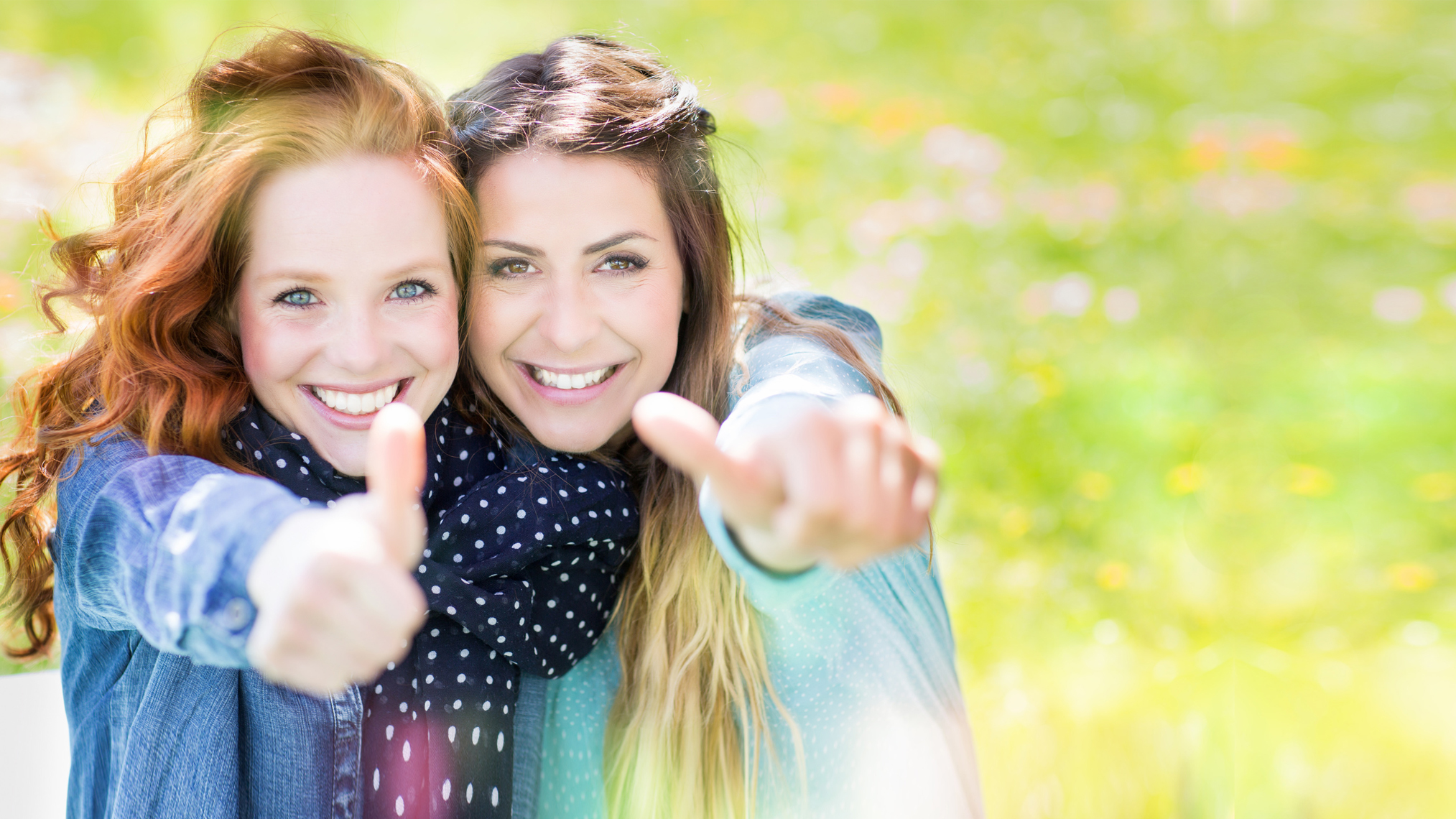 Zwei junge Frauen zeigen ihre Daumen hoch