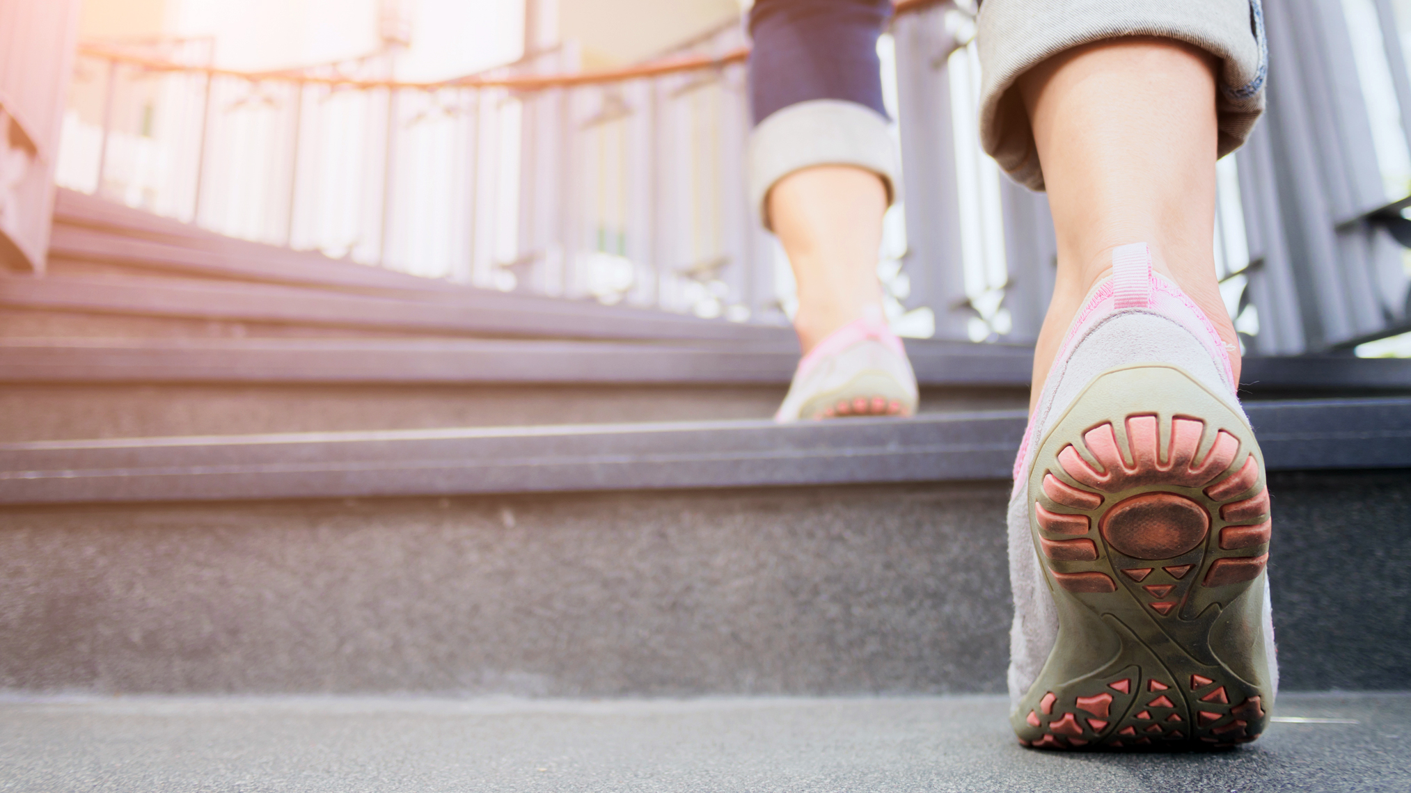 Detailaufnahme von Frauenfüßen in Schuhen, die eine Treppe hoch laufen