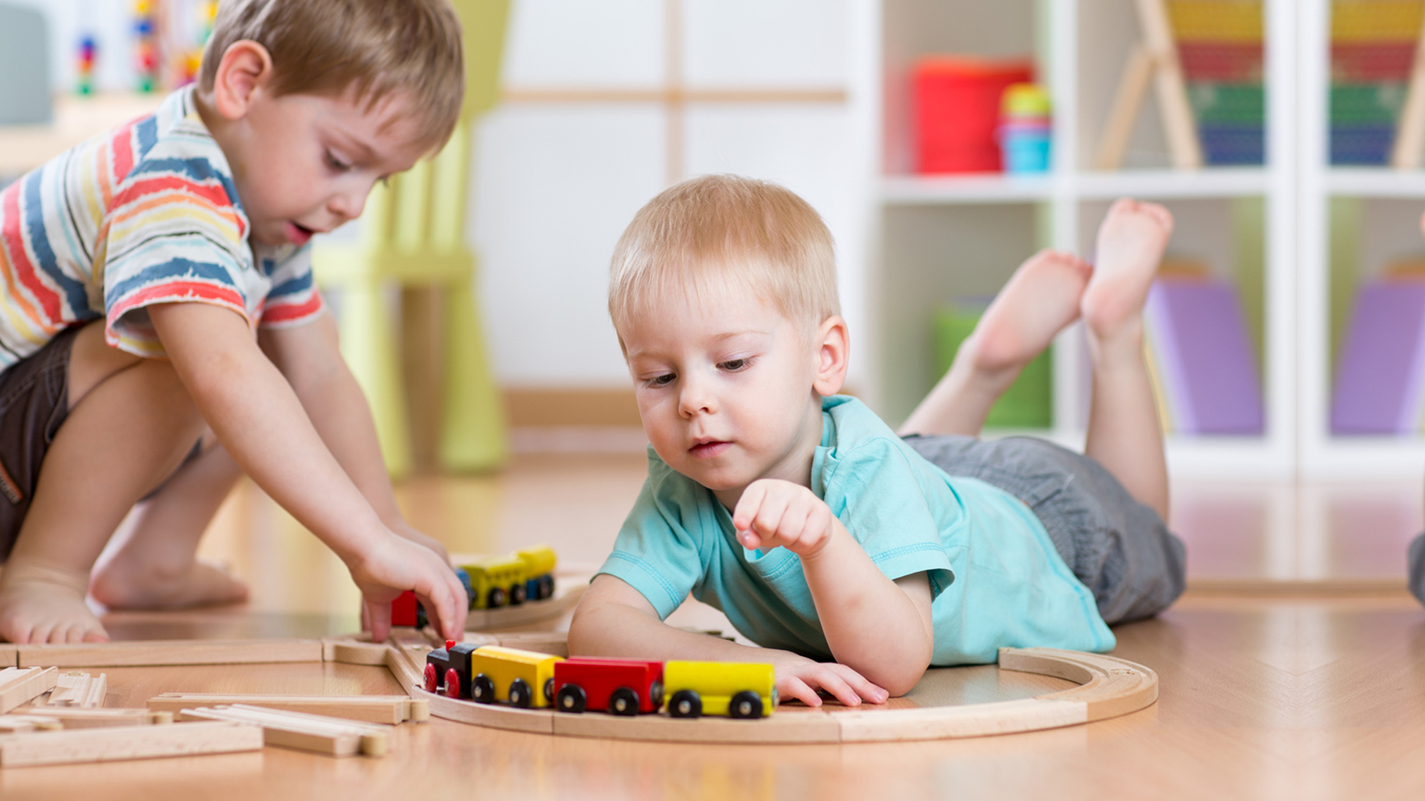 2 Jungen spielen auf dem Fußboden mit einer Eisenbahn