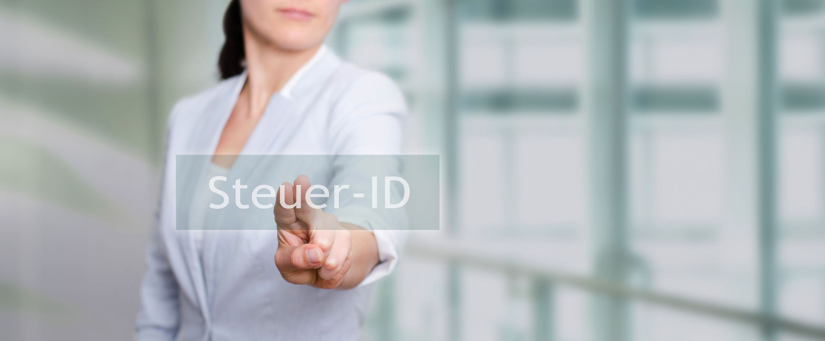 Die SteuerID Frau in einem weißen Jacke drückt auf eine transparente Schaltfläche im Vordergrund mit der Aufschrift "Steuer-ID"
