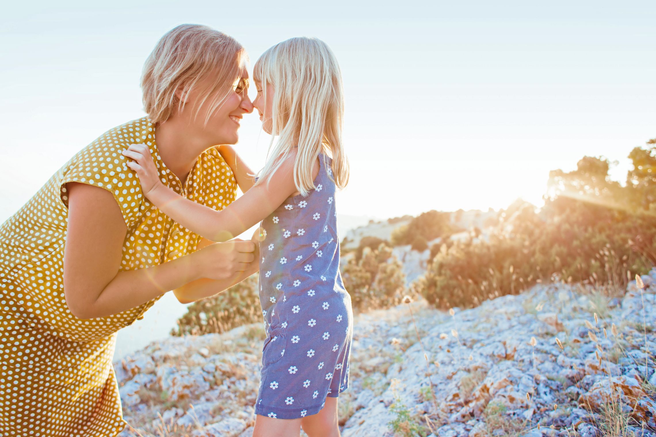 Mutter und Tochter geben sich lachend einen Nasenkuss