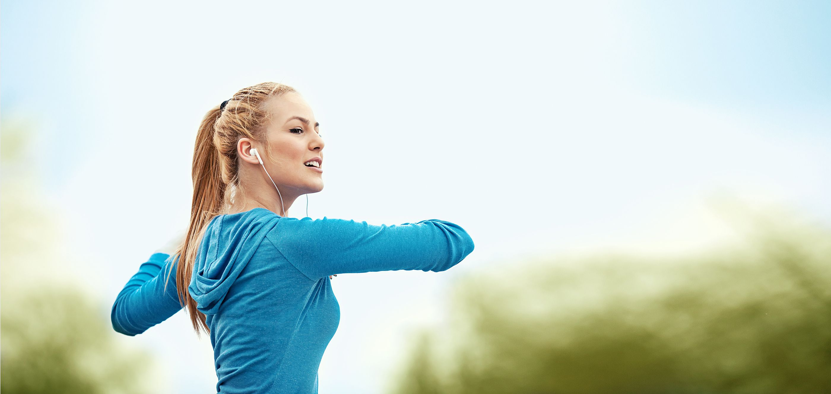 Blonde Frau mit einer türkisfarbenen Jacke bei ihrem Feierabend-Workout