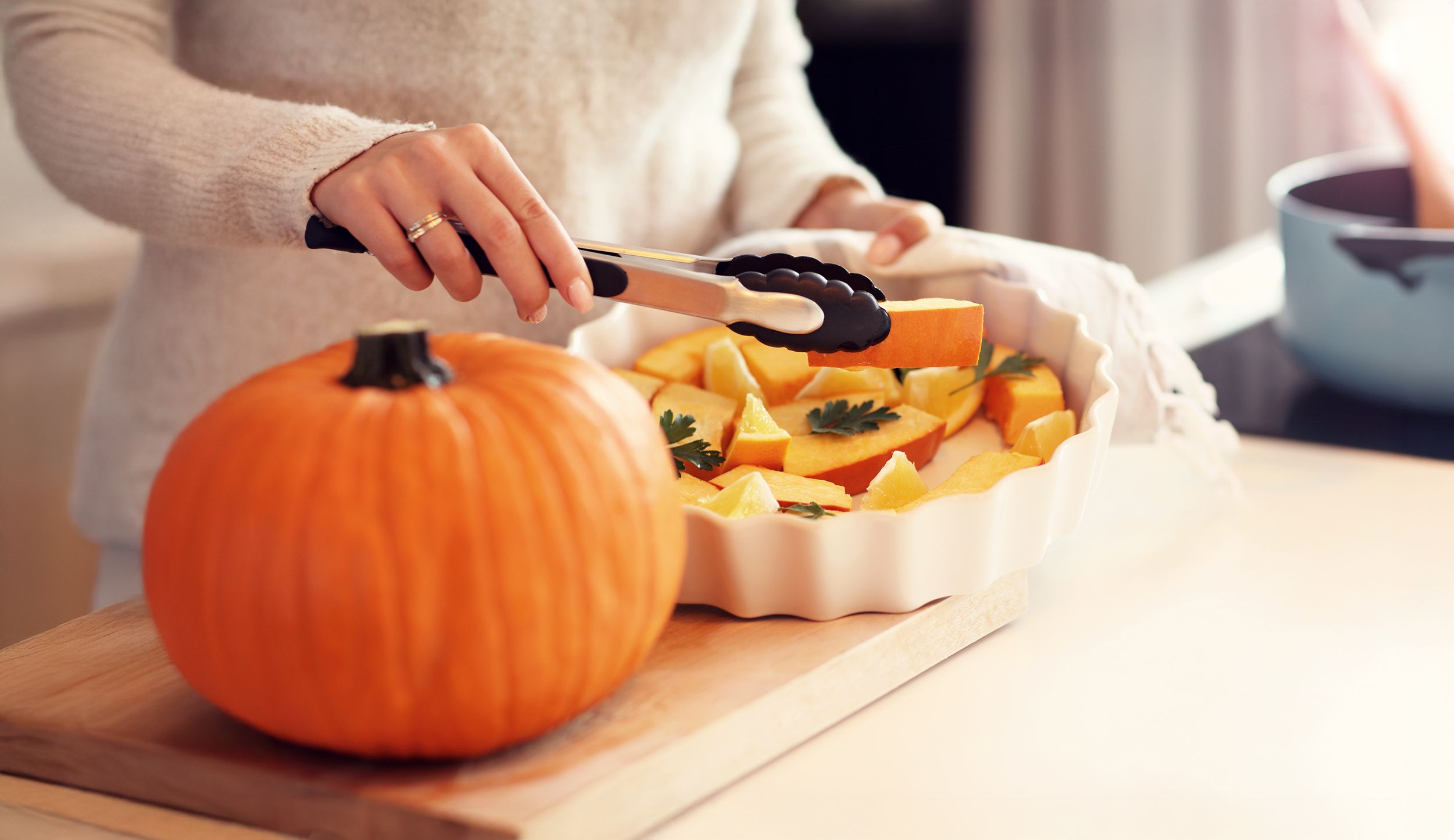 Frau bereitet Kürbis in einer weißen Auflaufform zu