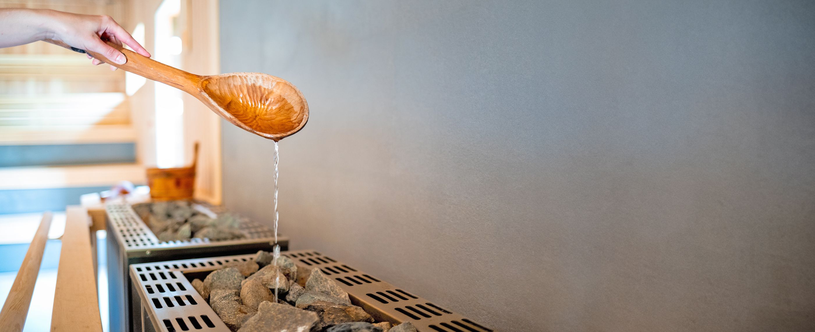 Großer Holzlöffel in einer Sauna, von dem Wasser herunterläuft