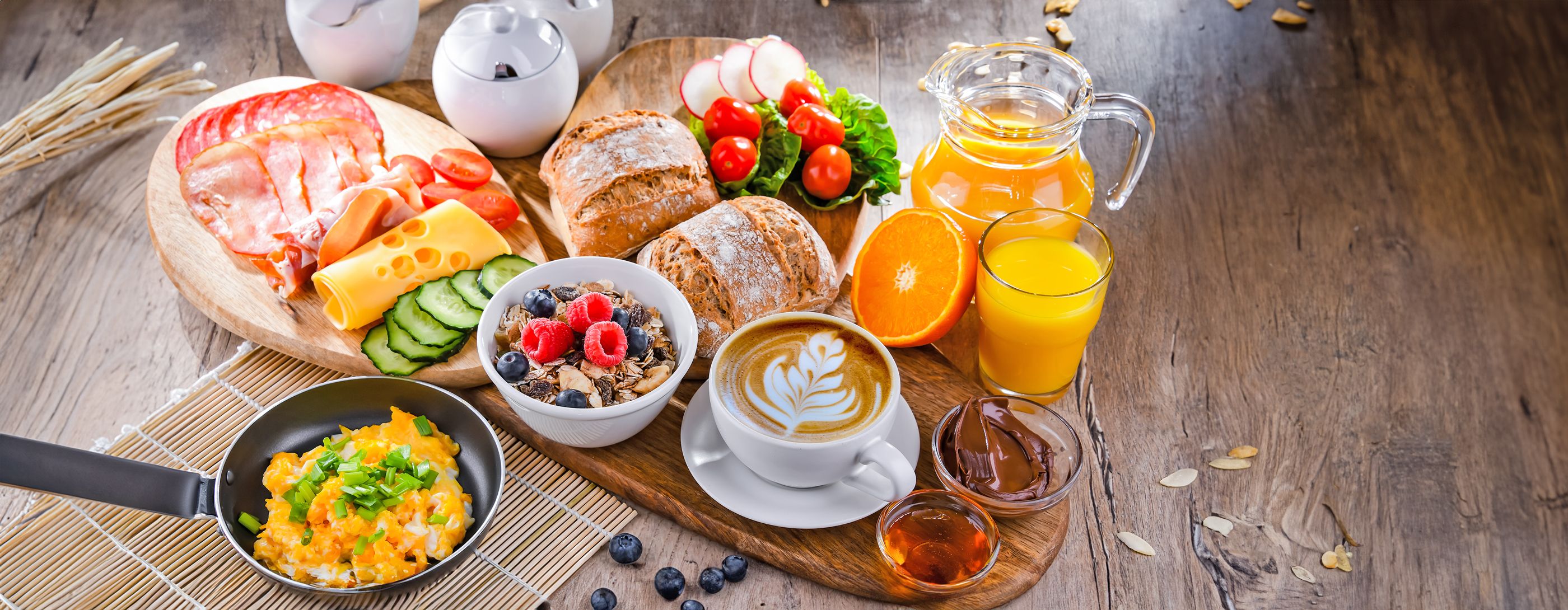 Rustikaler Holztisch gedeckt mit einem reichhaltigem und abwechslungsreichen Frühstück