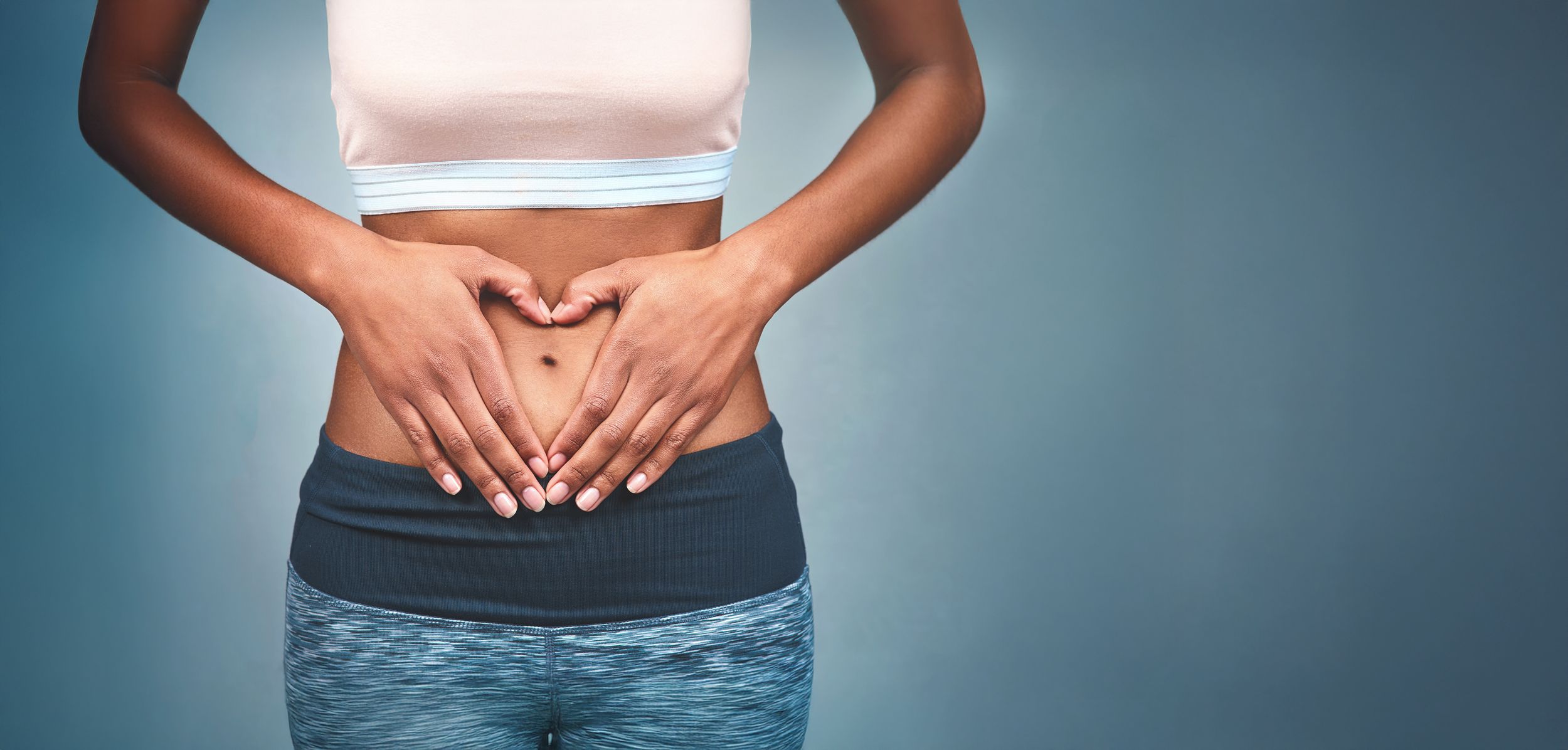 Sport und Verdauung Frau im Sportdress hält ihre Hände auf dem Bauch