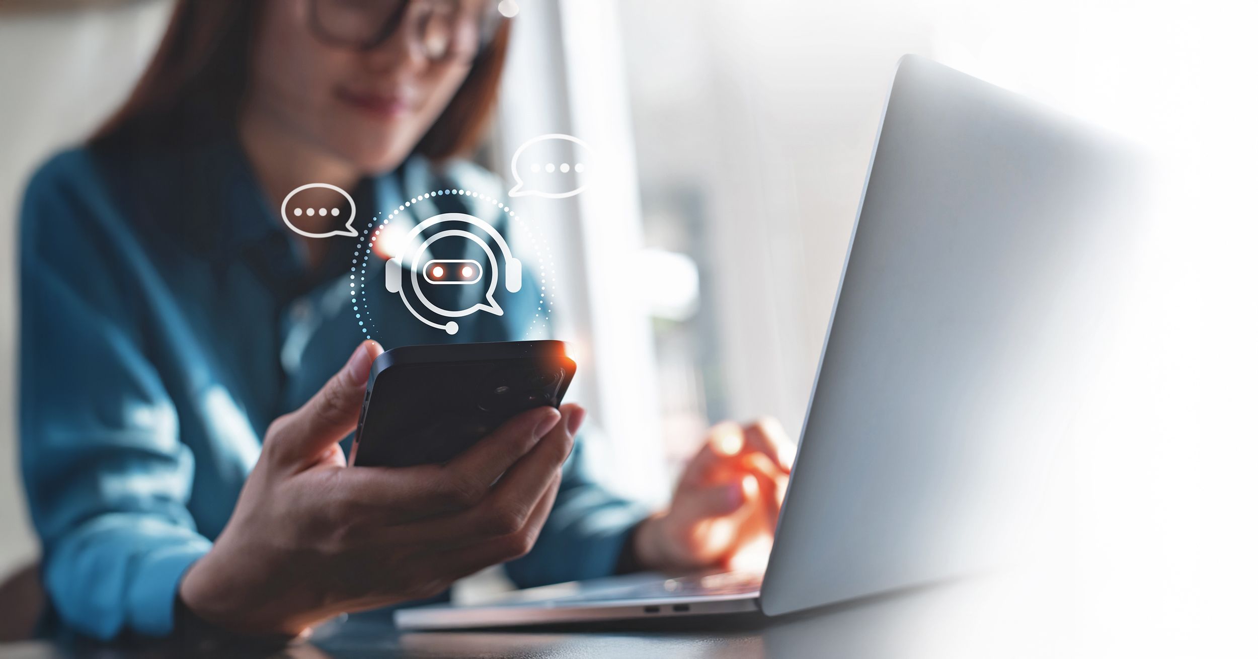 Frau mit Smartphone und Laptop nutzt eine KI
