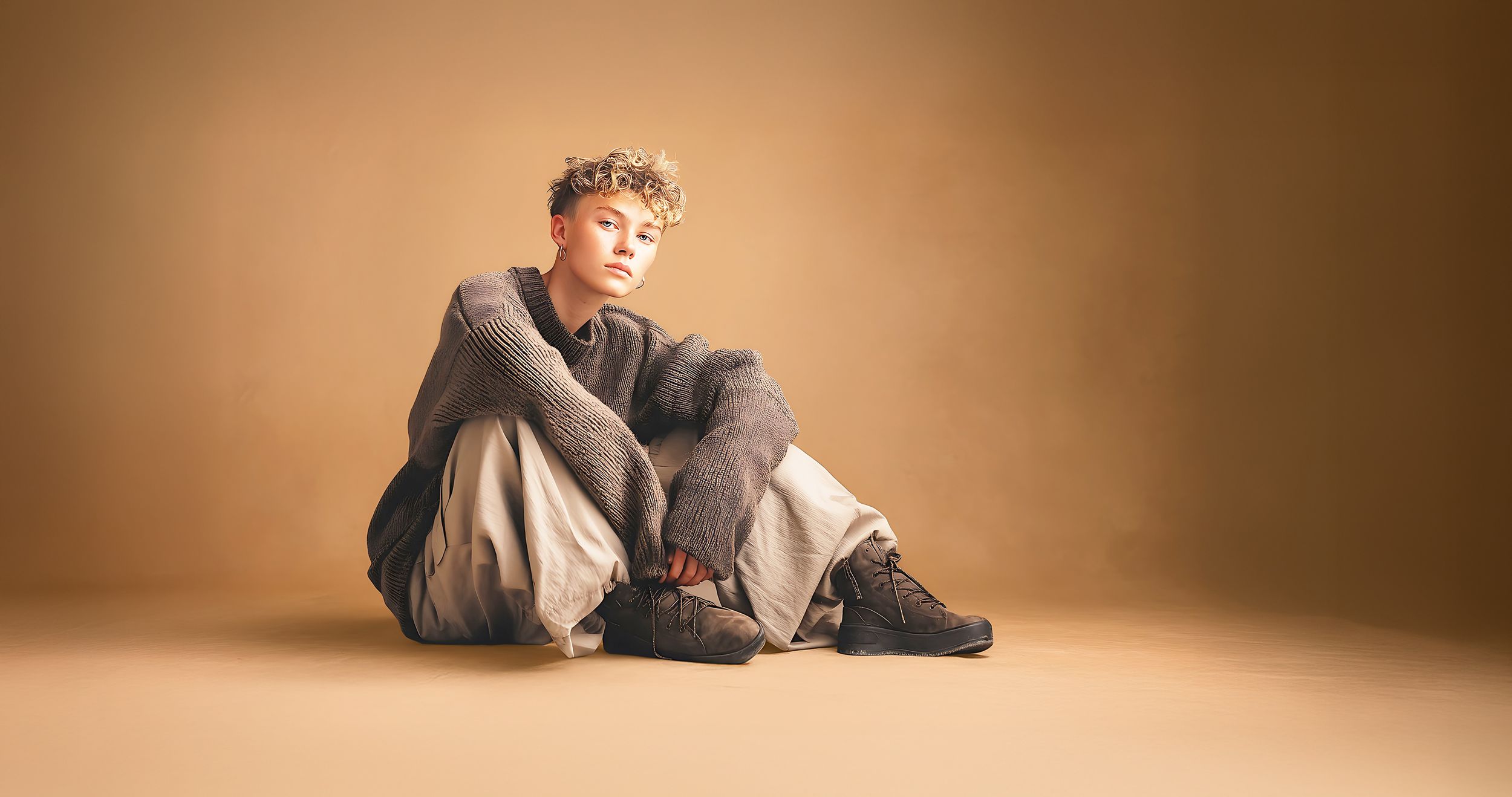 Jugendlicher im Schlabberlook sitzt lässig auf dem Fußboden