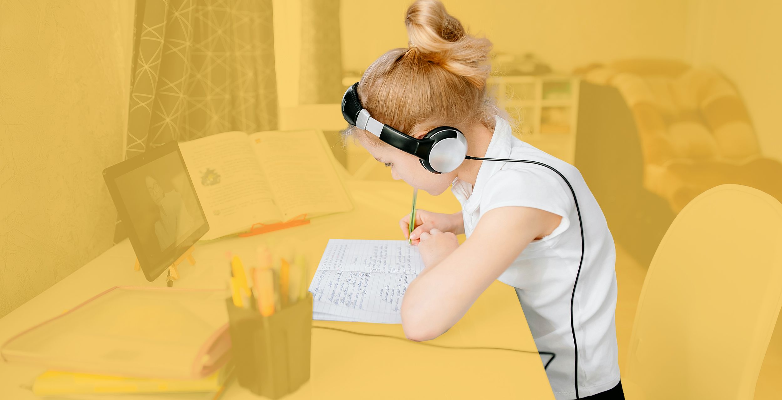 Schülerin am Schreibtisch mit einem Tablet und Kopfhörern