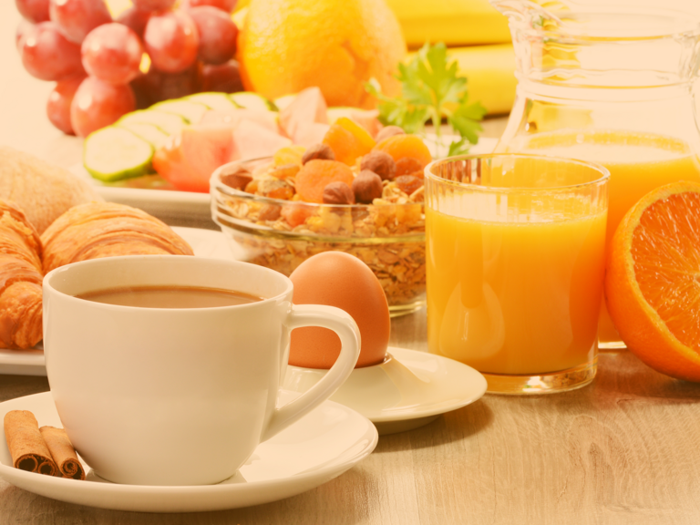 Lecker gedeckter Frühstückstisch mit Croissants, frischem o-Saft, Eiern, Müsli mit Früchten und Nüssen, ebenso eine Tasse Kaffee