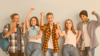 Portrait einer munteren Gruppe Jugendlicher vor einer hellblauen Wand