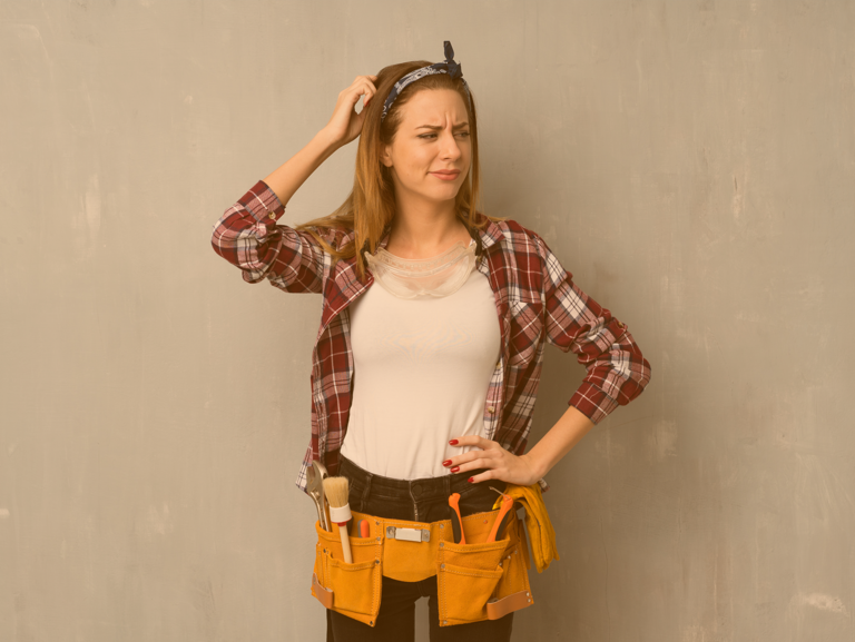 Auszubildende in Arbeitskleidung kratzt sich verlegen am Kopf und blickt dabei fragend zur Seite