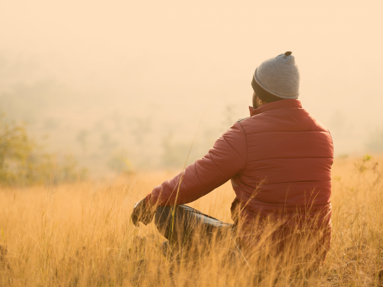Jugendlicher sitz im Lotussitz auf einer herbstlichen Wiese und genieß den Moment 