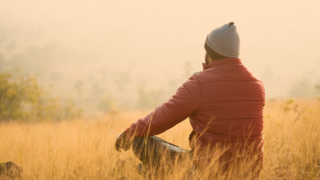 Jugendlicher sitz im Lotussitz auf einer herbstlichen Wiese und genieß den Moment 