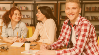 Gruppe Jugendliche sitzt am Tisch und arbeitet gemeinsam