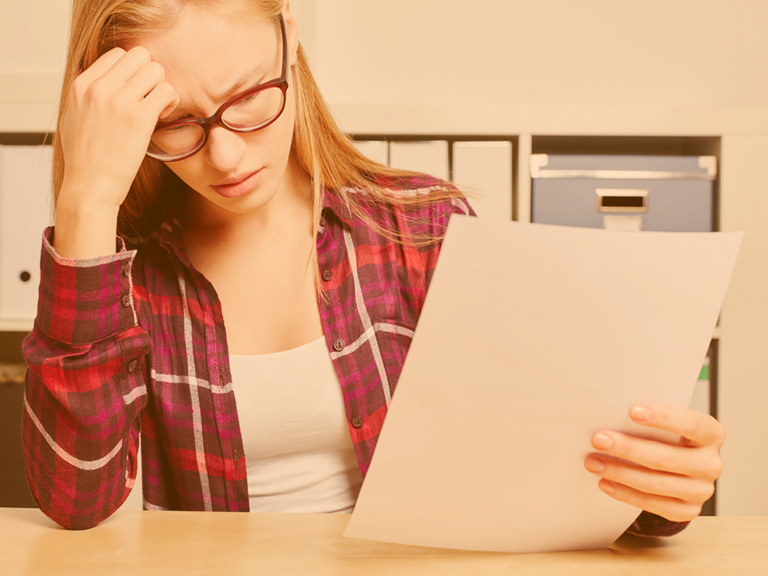 Junge Frau am Schreibtisch sitzend liest Brief besorgt